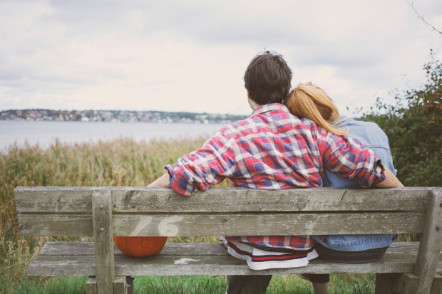 Pāris sēž uz soliņa pie ezera
